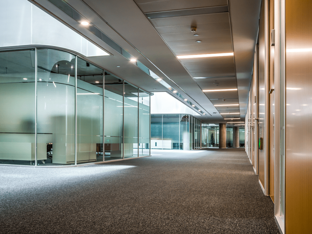 A large empty room with glass walls and a carpet floor.