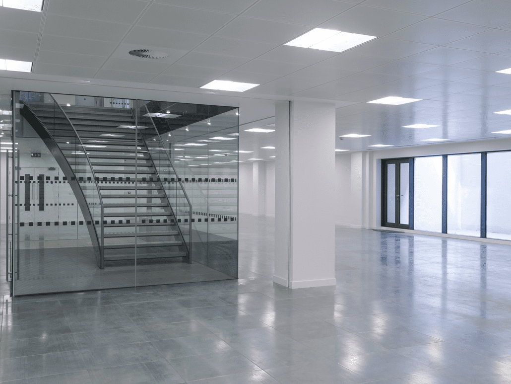 A large empty room with glass walls and stairs.