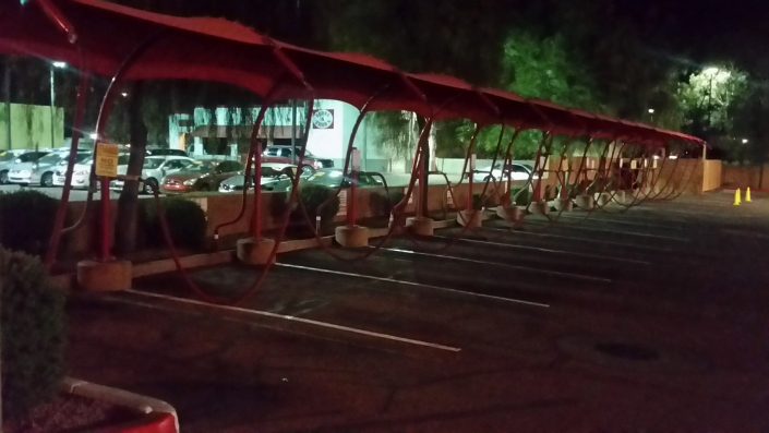 A parking lot with several red umbrellas in the dark.