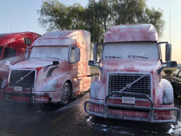 Two semi trucks are parked in a parking lot.