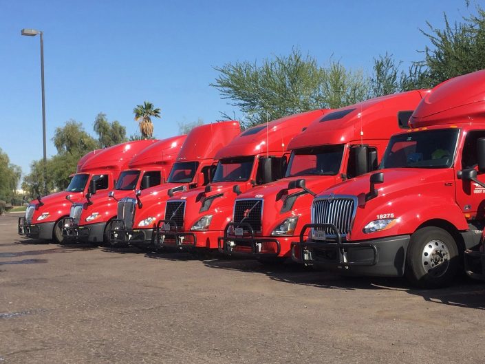 A row of red semi trucks parked in a lot.