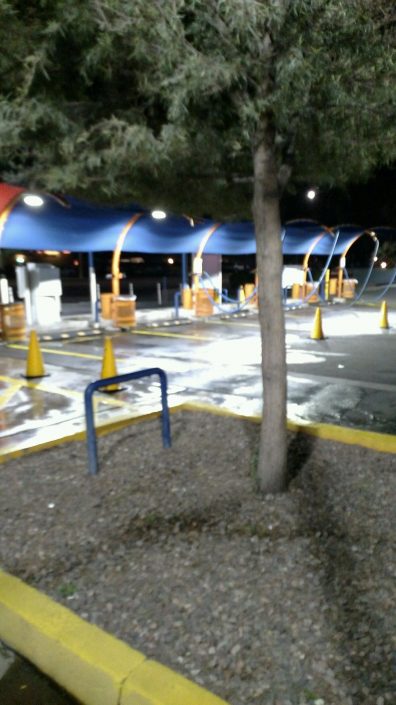 A parking lot with trees and benches in the background.