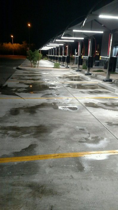 A parking lot with many spots of water on the ground.