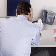 A man holding his head in front of the wall.